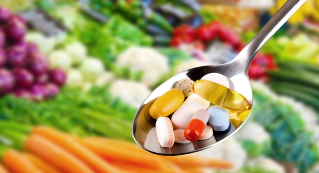 Supplements in Spoon with Vegetables in Background Blurred