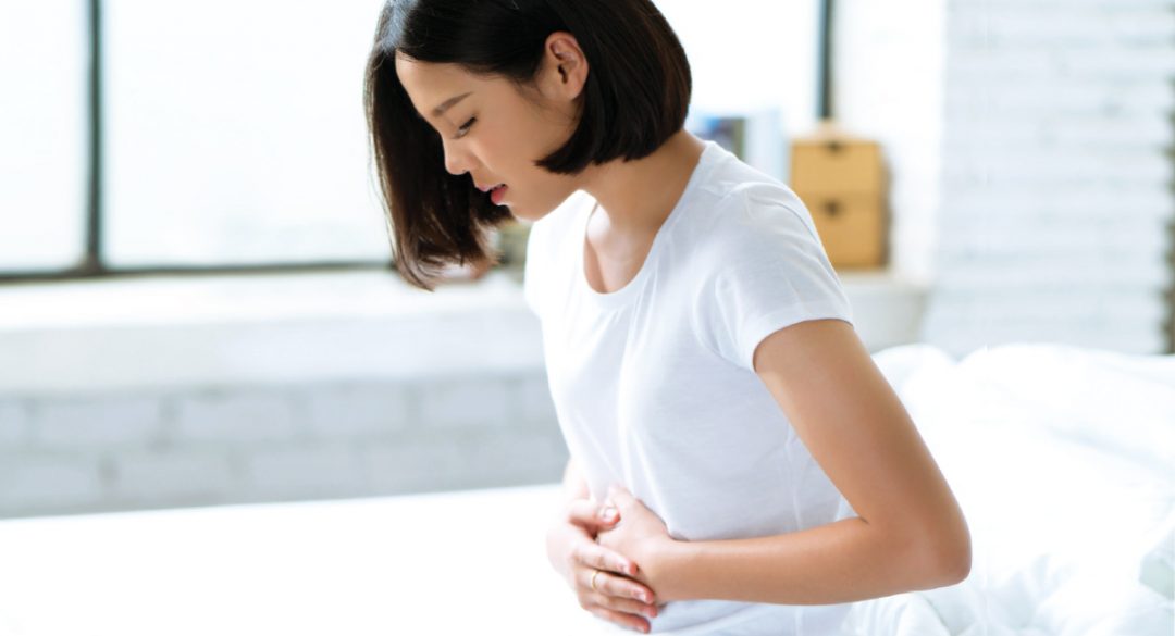 Woman in White with Stomach Pain